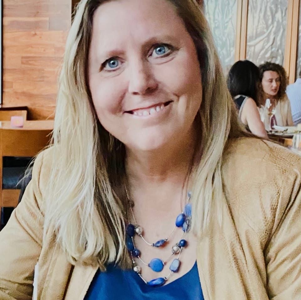 Patti Aldridge smiling at the camera, wearing a blue beaded necklace.